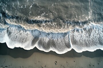 Wall Mural - Waves crashing on sandy shore at sunset, creating a tranquil coastal atmosphere