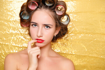 Wall Mural - Beautiful girl in hair curlers isolated on gold