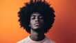 © pngking - Vibrant portrait of a young man featuring a stylish afro hairstyle against a bold orange background