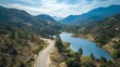 © rehan - Winding Road Through Mountainous Landscape Beside Serene Lake