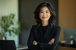 © Oksana - Portrait of a smiling Asian businesswoman in a black suit in a modern office setting