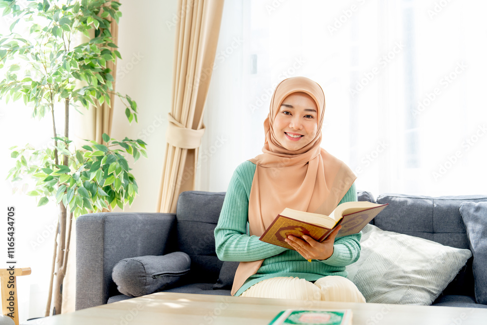 Asian beautiful muslim woman sit on sofa in her house and read the book ...