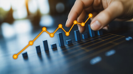 Wall Mural - Person is touching a graph with a blue line and orange dots. The graph is a line graph, and the blue line represents a trend or pattern. The orange dots are used to mark specific points on the graph