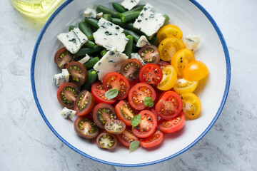 Wall Mural - Salad with cherry tomatoes, green beans and blue cheese served in a white and blue plate, horizontal shot, middle closeup