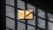 © Taufik - A tan envelope on a dark brick wall with window shadows.