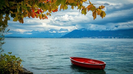 Wall Mural - A serene view of lake geneva with a solitary red boat floating peacefully the majestic alps rise in the background under a cloudy sky, framed by vibrant foliage.