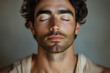 © hkjdesign - Close-up portrait of a young man with his eyes closed, showcasing his facial features and stubble.