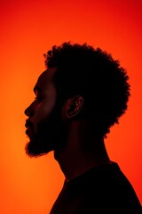 Minimalist portrait of an African man's silhouette against a vibrant orange background