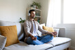 © Daniel - Man meditating on the couch listening to guided meditation using wireless headphones.