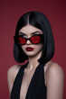 © Magdalena Wojaczek - Stylish Woman Red Sunglasses Black Bob Hair Red Background Fashion Portrait