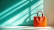 © Dulemegapixel - An orange tote bag stands strong against a backdrop of turquoise and soft light, highlighting simplistic design and vibrant color, suggesting a bold fashion statement.