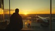 © Thiga.project - A traveler stands at an airport window, looking out at the runway.