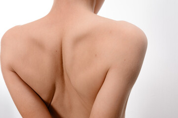 A detailed image showcasing the back and shoulders of a person, highlighting skin texture and form. The neutral background accentuates the subject's anatomy.