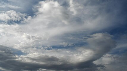 Wall Mural - time lapse of white and gray clouds moving across a dark blue sky.