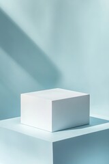 Poster - Minimalist White Cube on a Light Blue Pedestal With Soft Shadows Creating a Serene, Modern Aesthetic in a Studio Setting During Daytime