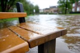 Flooded park bench reflects stormy weather and rising waters on a gloomy afternoon