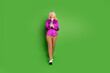© deagreez - Full size photo of attractive retired woman hold device walking dressed stylish violet satin clothes isolated on green color background