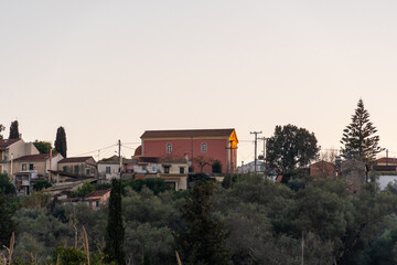 Wall Mural - Sunset over a village with a prominent pink building.