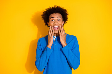 Wall Mural - Photo portrait of attractive young man excited touch cheeks dressed stylish blue clothes isolated on yellow color background