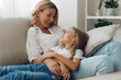 © SHOTPRIME STUDIO - Mother and daughter bonding time on a cozy white couch, sharing a heartfelt moment in a bright living room