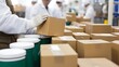 © Aditya - A worker in a cleanroom places a cardboard box onto a stack of similar boxes.  Other workers are visible in the background, blurring into the factory setting.