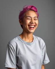 Wall Mural - Joyful Young Woman with Pink Hair Laughing Against a Gray Background