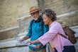 © Mediteraneo - Portrait of happy senior couple tourists outdoors in historic town using map.