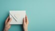 © Chatchai - A person holds a white envelope with a heart decoration against a teal background, suggesting an invitation or heartfelt message.