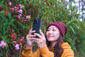 a woman taking photos of wild flowers with smartphone in the forest