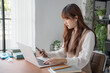 © Charlie's - Asian woman using laptop to study student engaged in online learning at college