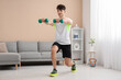 © Pixel-Shot - Young man training with dumbbells at home
