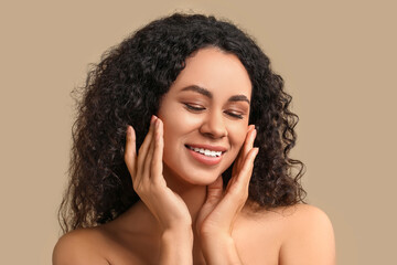 Beautiful young happy African-American woman with healthy skin on beige background