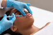 © Prostock-studio - Black lady getting lip filling injection at modern beauty salon, closeup, copy space