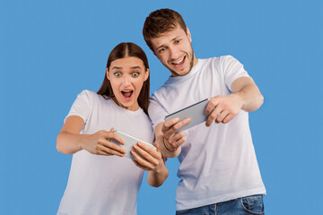 Poster - Portrait of excited friends playing games using cell phones isolated over purple studio wall, isolated