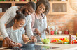 © Prostock-studio - Kind afro parents teaching their adorable daughter how to cook healthy food in kitchen, copy space