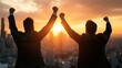 © JoxyAimages - Two entrepreneurs stand together toasting with their arms raised against a breathtaking sunrise, symbolizing joint success, optimism, and the dawn of new opportunities.