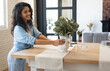 © Prostock-studio - Modern home interior design, Scandinavian style concept. Beautiful young brunette woman arranging plants in vase, decorating dining room table, creating cozy atmosphere in her apartment, copy space