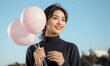 © RooftopStudioBangkok - young woman joyfully holds pastel pink balloons against clear blue sky, exuding happiness and warmth. Her casual attire and serene outdoor setting create relaxed and cheerful atmosphere