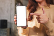 © Farknot Architect - Mockup image of a woman holding and pointing finger at a mobile phone with blank white screen