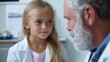 © Iona - A young girl listens intently to a bearded doctor in a coat, discussing important medical details in a bright, clinical setting.