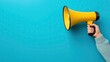 © Simona - Hand holding yellow megaphone on blue background with copy space