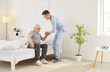 © Studio Romantic - Caring male doctor or nurse helping a senior patient get out of bed after wake up in the morning at a nursing home. Compassionate healthcare, morning routines, and essential assistance.