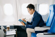 © Nuttapong punna - Young Asian executive excels in first class, multitasking with digital tablet, laptop and smartphone.