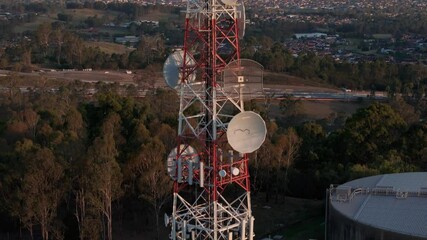 aerial drone close up view slowly rising up above a tall mobile telecommunication cell tower on a co
