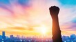 © mashimara - A raised fist silhouetted against a glowing sunset in a city protest, symbolizing unity, strength, and the fight for justice and equality.