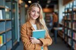 © velikiyzayats - Smiling young woman holding a book in a library, perfect for educational, motivational, and inspirational content.