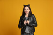 © New Africa - Woman with cat makeup and ears in leather jacket on orange background