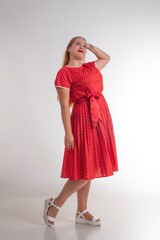 Young beautiful girl posing in red polka dot dress on a white background.