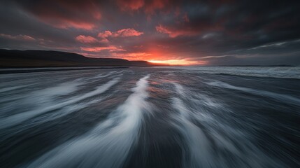 Aufkleber - A dramatic sunset over a beach with waves creating a dynamic foreground.