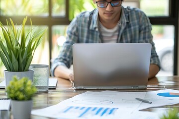 Poster - Person working on laptop at desk with charts and plants